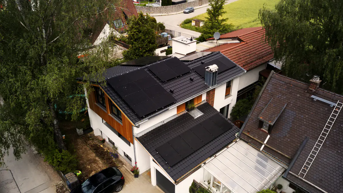 Neu eingedecktes Dach mit Photovoltaikmodulen und Holzfassade